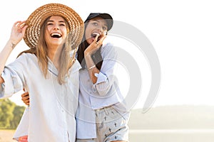 Two beautiful young women strolling on a beach. Female friends walking on the beach and laughing on a summer day.