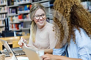 Two beautiful young women studying in a university library.