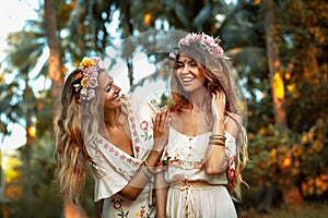 Two beautiful young woman in summer dresses outdoors at sunset