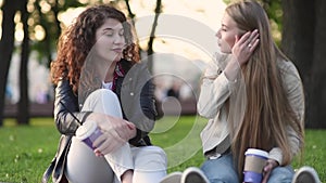 Two beautiful young women talking and drinking coffee outdoors