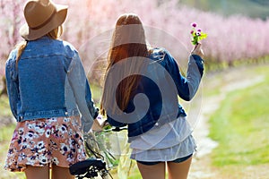 Two beautiful young women with a vintage bike in the field.