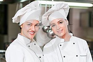 A two beautifull young female chef posing for camera