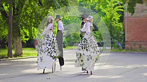 Two beauty couples on stilts are dancing on the street