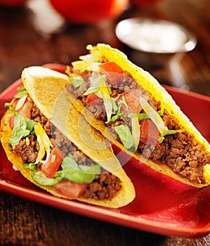 Two beef tacos with cheese, lettuce and tomatoes