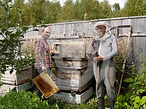 Two beekeepers work about a beehive