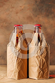 Two beer bottles are in brown paper bags