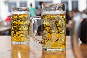 Two beer glasses in german biergarten background