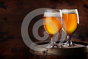 Two beer glasses on wooden barrel