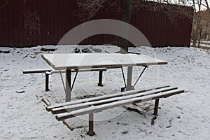 Two benches and a table covered with snow