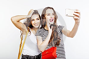 Two best friends teenage girls together having fun, posing emotional on white background, besties happy smiling, making