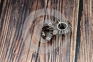 Two bevel gears after manufacturing lie on a wooden background