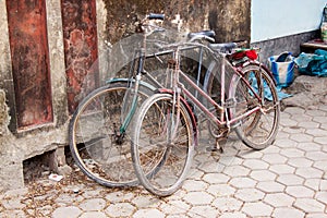 Two bicycles lean against a wall