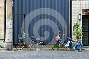 Two bicycles park in front of steel wall