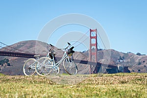 Two bicycles parked on grass in front of Golden Gate Bridge