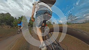 Two bicyclists friends ride cross-country mountain bikes along field path. Action camera shot with ultra wide-angle lens