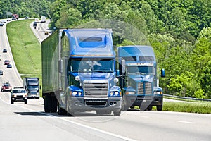 Two big blue trucks on a highway