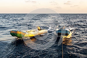 Two big fast empty dinghy being towed by a diving motor boat, Red Sea, Sudan