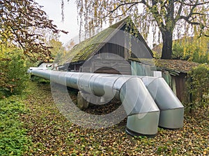 Two big heat pipes outdoors near old house in the city.