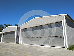 Two big industrial metal hangar or warehouse with closed doors. Metal garage building for manufacturing usage.