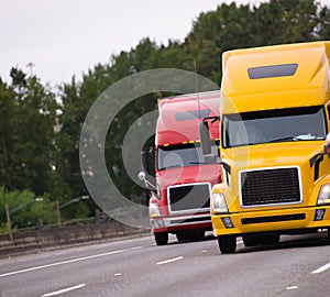 Two big rig semi trucks running side by side on the road