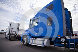 Two big rigs semi trucks tractors standing on the parking lot in