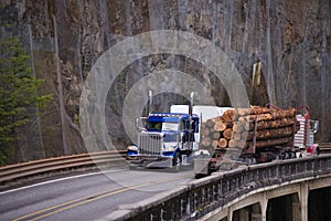 Two big rigs semi trucks transporting cargo moving towards each