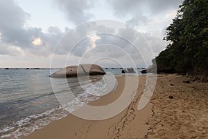 Two big rocks in la piscina beach located into tayrona park with orange sunset photo