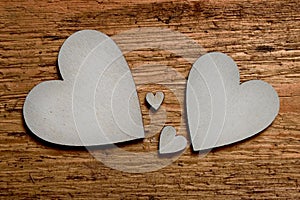 Two big silver wooden hearts, two small hearts between them on wooden background. Symbol of two parents and two children