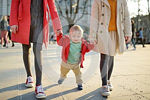 Two big sisters and their baby brother having fun outdoors. Two young girls holding their baby boy sibling on sunny spring day.