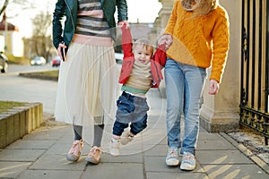 Two big sisters and their baby brother having fun outdoors. Two young girls holding their baby boy sibling on sunny spring day.