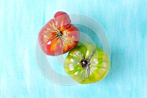 Two big tomatoes of green and red colors