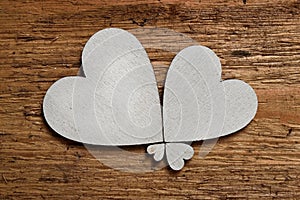 Two big white wooden hearts and two small hearts on rough wooden background. Symbol of four leaf clover