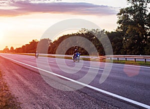 Two bikers are driving on a motorway on a country road in the summer against the background of a sunset. Copy space for