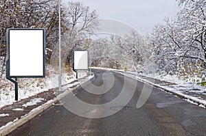 Two billboards on country asphalt road with tree covered with snow an sky nature background