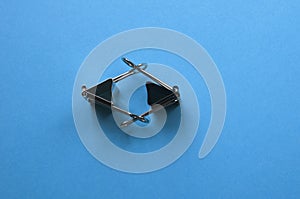 Two binder clips close up on a blue background in the image of characters holding hands, selective focus