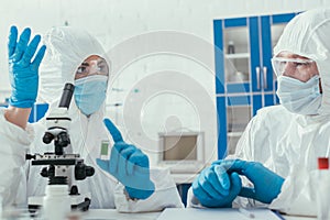 Two biochemists in hazmat suits talking in laboratory