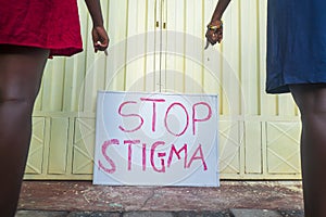 Two black female hands pointing to sign with text Stop Stigma``