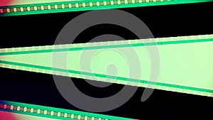 Two black film strips on green background close up. 35mm film slide frame. Copy space.