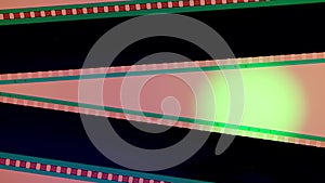 Two black film strips on pink background illuminated with green neon circular light, close up. Copy space.