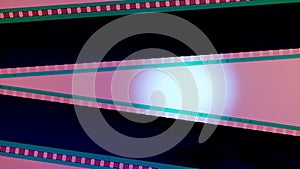 Two black film strips on pink background illuminated with white circular light, close up. Copy space.