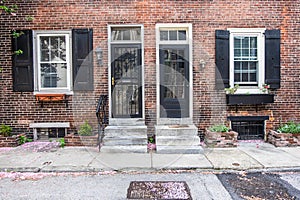 Two black front doors entrance and old-style window with shutters of a red brick house in spring.