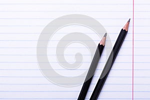 Two black graphite pencils on white sheet in line Copy space Back to school, education concept