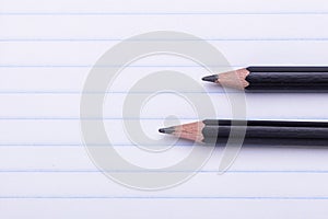 Two black graphite pencils on white sheet in line Copy space Back to school, education concept