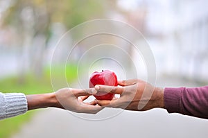 Two black hands keeping a red apple