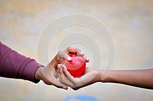 Two black hands keeping a red apple