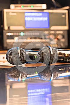 Two black microphones in a Japanese karaoke box room with a machine in background.