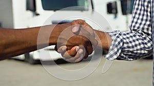 Two black people shaking hands on truck parking, close up
