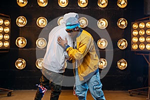 Two black rappers in caps hugging on stage