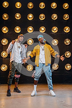 Two black rappers in caps poses on stage