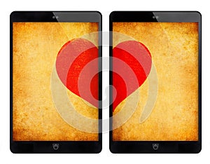Two black tablet with red heart on grunge wall.
